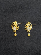 Gold earrings with intricate designs on a black background