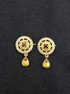 Gold earrings with red gemstones on a black background