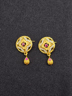 Pair of gold earrings with red gemstones on a black background