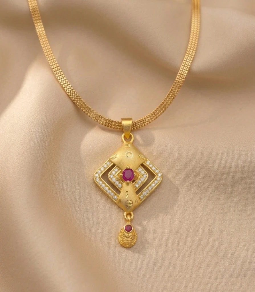 Gold necklace with a diamond-shaped pendant on a beige fabric background