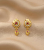 Gold earrings with red gemstones on a beige fabric background