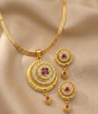 Gold jewelry set with circular pendants and earrings on a beige fabric background