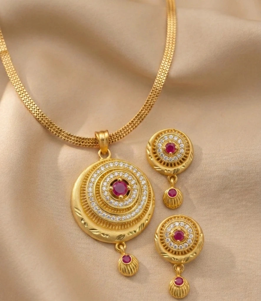 Gold jewelry set with circular pendants and earrings on a beige fabric background