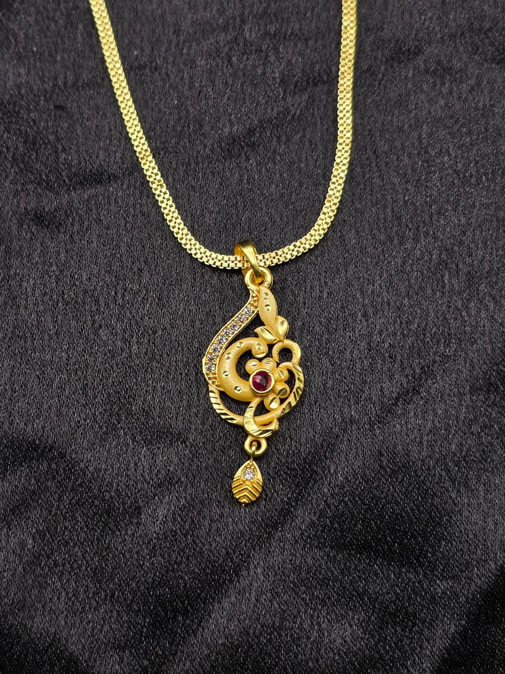 Gold necklace with a decorative pendant on a black fabric background