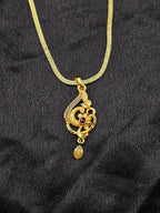 Gold necklace with a decorative pendant on a black fabric background