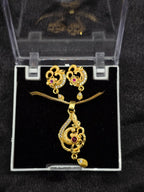 Gold necklace and earrings set in a clear box on a black background