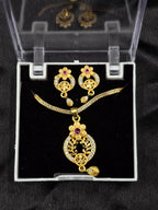Gold necklace and earrings set in a clear display case on a black background