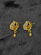 Gold earrings with gemstones on a black fabric background