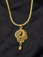 Gold necklace with a pendant featuring a red gemstone on a black background