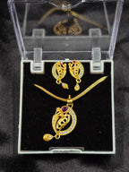 Gold jewelry set with necklace and earrings in a clear display case on a black background