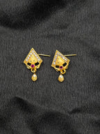 Gold earrings with gemstones on a black fabric background
