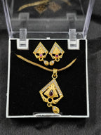 Gold necklace and earrings set in a clear display case on a black background
