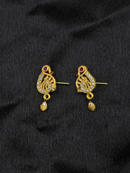 Pair of gold earrings with intricate designs on a black fabric background