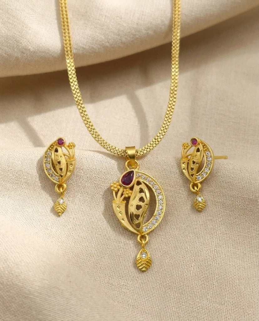 Gold necklace and earrings set on a beige fabric background