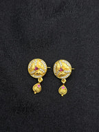 Gold earrings with red gemstones on a black fabric background