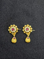 Pair of gold earrings with red gemstones on a black background