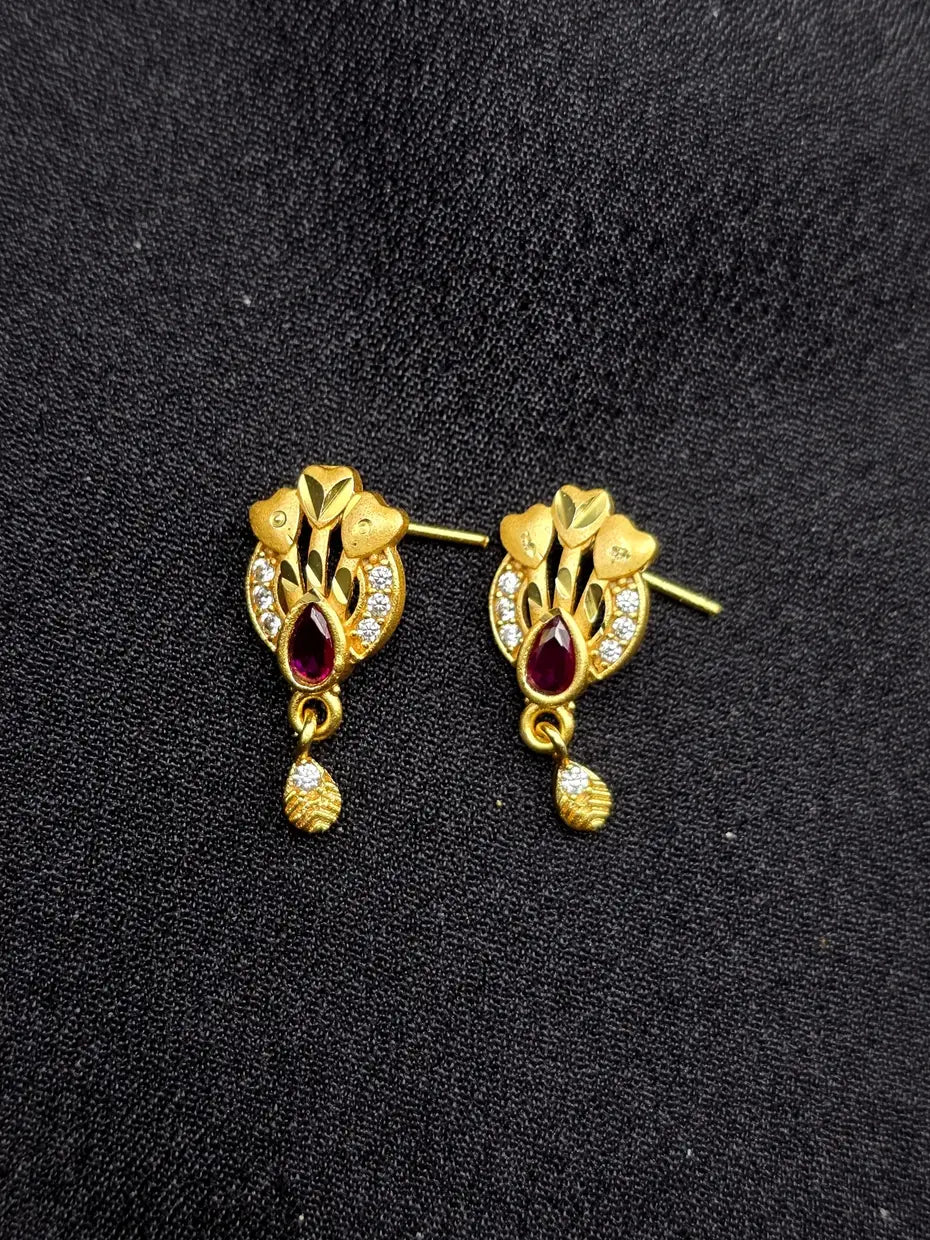 Gold earrings with red gemstones on a black background