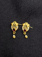 Gold earrings with red gemstones on a black background