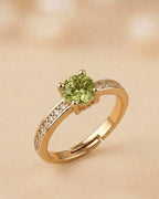 Gold ring with a green gemstone on a beige background