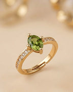 Gold ring with a green gemstone on a beige background