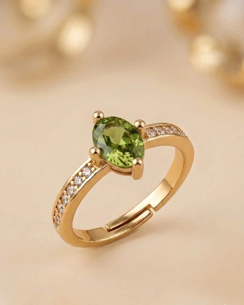 Gold ring with a green gemstone on a beige background