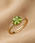 Gold ring with a green gemstone on a gold background