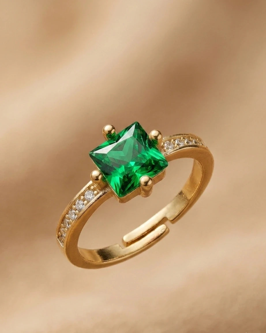 Gold ring with a green gemstone on a beige background