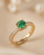 Gold ring with a green gemstone on a beige background