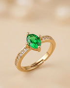 Gold ring with a green gemstone on a beige background