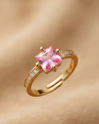 Gold ring with a pink gemstone on a gold background
