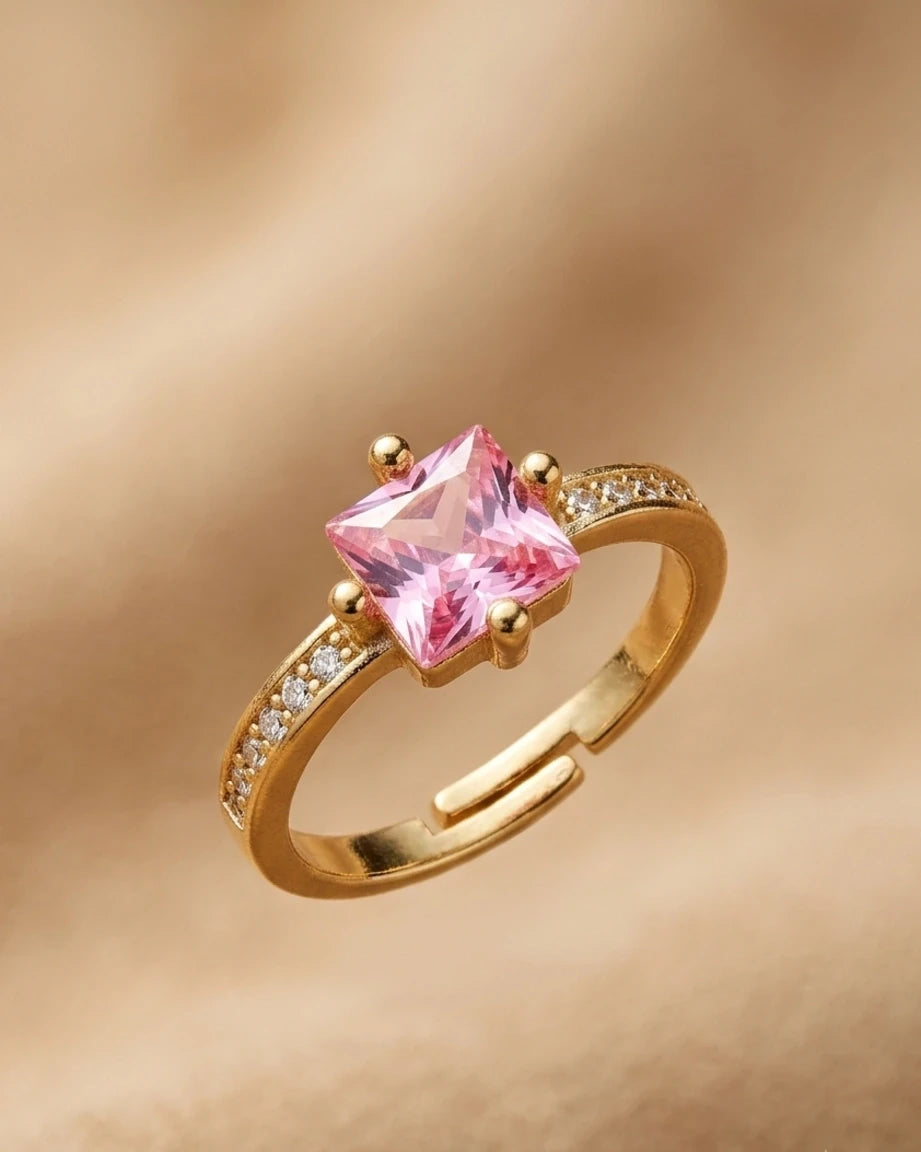 Gold ring with a pink gemstone on a gold background