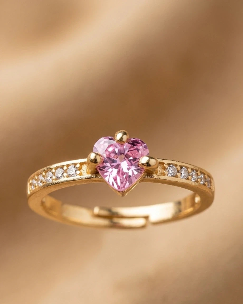 Gold ring with a heart-shaped pink gemstone on a gold background