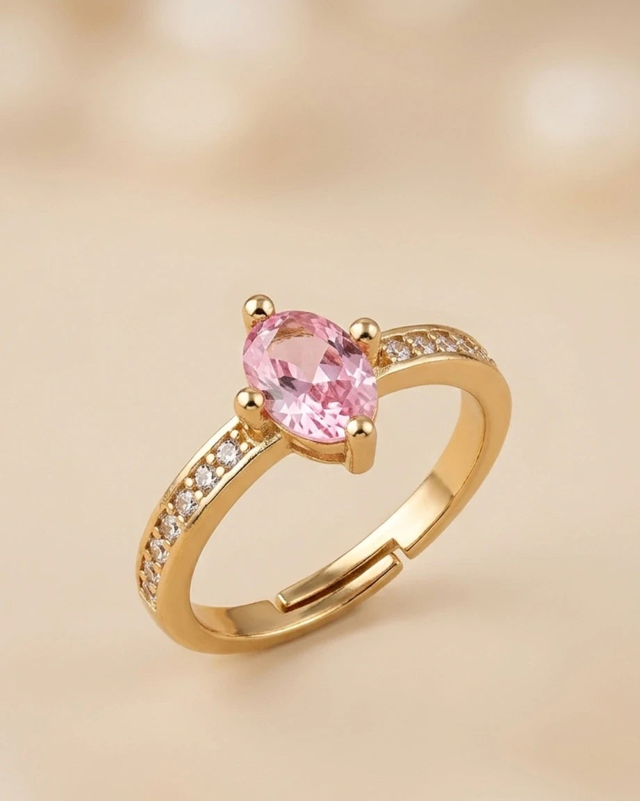 Gold ring with a pink gemstone on a beige background