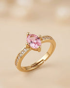Gold ring with a pink gemstone on a beige background