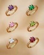 Set of six gold rings with colorful gemstones on a beige background
