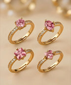 Four gold rings with pink gemstones on a beige background