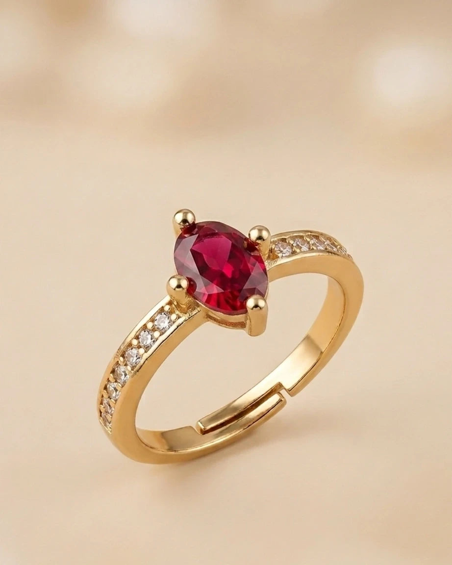 Gold ring with a red gemstone on a beige background