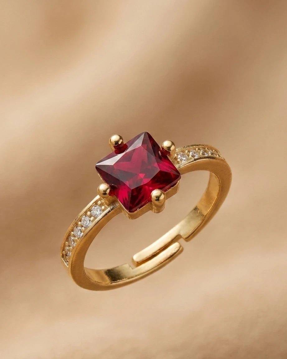 Gold ring with a red gemstone on a gold background