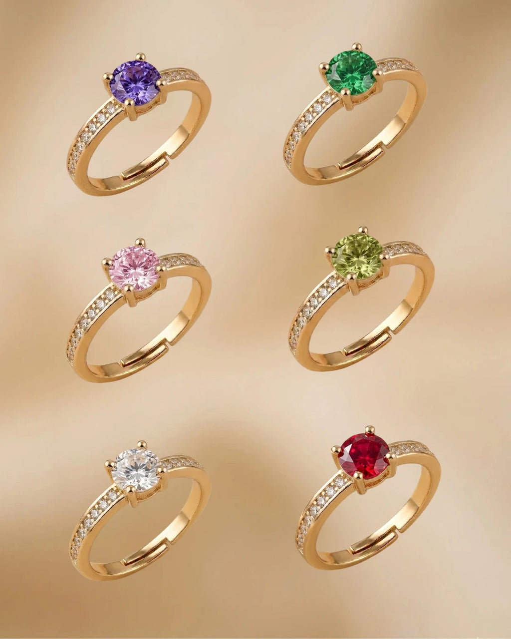 Set of gold rings with colorful gemstones on a beige background